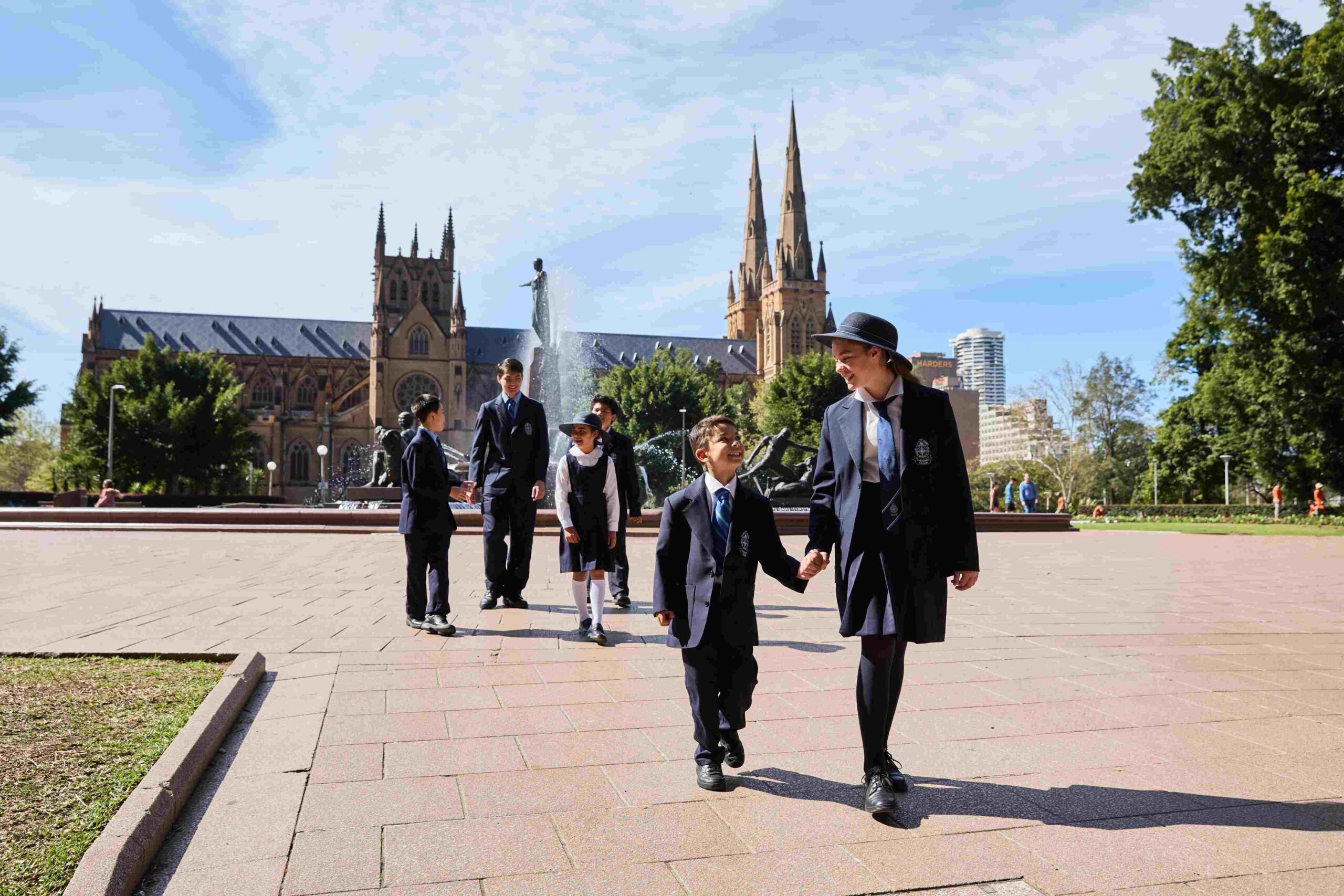 Male and female students walk near the fountain in Hyde Park with the beautiful St Mary's Cathedral in the background.